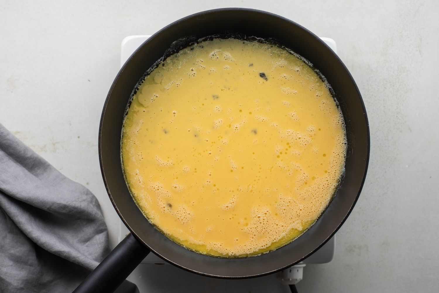 Beaten eggs covering the bottom of the frying pan